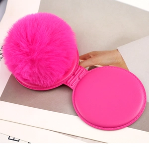 Close-up of vibrant pink faux fur and folding mechanism on a compact portable makeup mirror