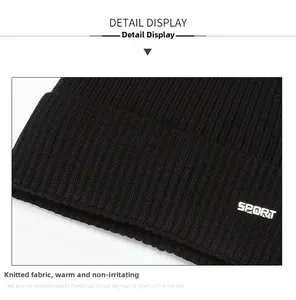 Detail of black ribbed knit fabric with a silver SPORT metal tag on the beanie