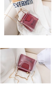 Detail of transparent PVC crossbody bag with golden cat-ear handle and red inner pouch