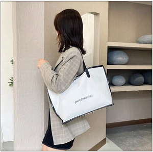 White minimalist tote bag with black trim shown on model for size and style perspective