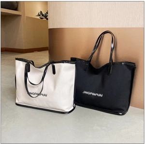 Detail view of beige and black tote bags with large capacity and lettered logo print