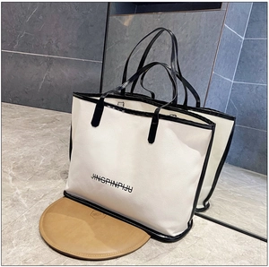Detail of white tote bag with black handles and JINGPINPIJU lettering on marble floor