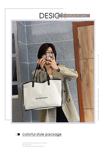 Close-up of a large white tote bag with black trim and handles in a mirrored selfie view