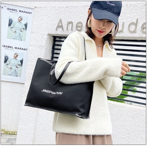 Outdoor model shot showing the capacity of a black large tote bag with white lettering