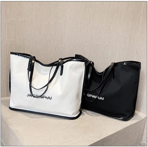 Black and white canvas tote bags with high-contrast lettering and leather trim detail