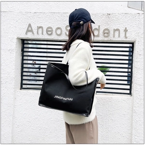 Minimalist black tote bag shown on model with shoulder strap for daily commuting