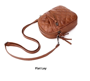 Detail view of brown quilted crossbody bag featuring triple-zipper storage compartments