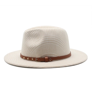 Detail of beige houndstooth fedora hat with brown leather strap and gold metal studs