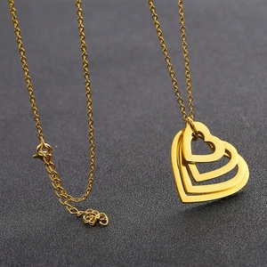 Golden double heart pendant necklace with elegant chain on a dark textured background
