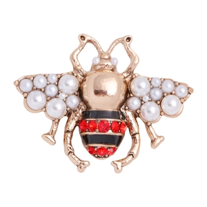 Elegant gold bee brooch with white pearls and red rhinestone accents on white background