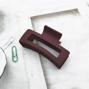 Detail of a matte deep red square hair claw clip on a minimalist white cotton background