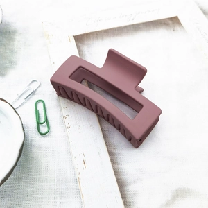 Detail of large matte dusty rose hair claw clip for elegant styling on fabric background