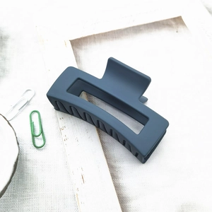 Close-up of a matte navy blue square hollow hair claw clip on a rustic linen backdrop