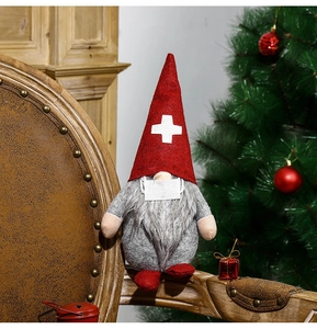Gnome de Noël avec masque posé sur une chaise en bois devant un sapin décoré de fêtes