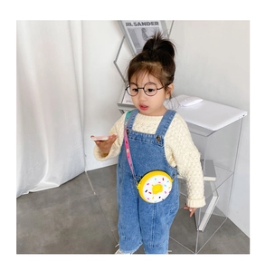 Détail du sac donut en silicone jaune avec bandoulière arc-en-ciel sur un enfant