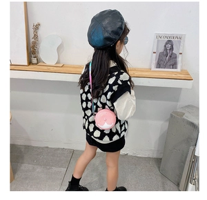 Detail of pink round kids crossbody bag with colorful strap worn by a young model
