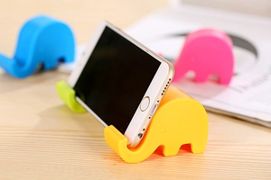 Colorful elephant-shaped phone stands in pink and blue on a wooden desk setup