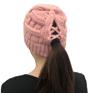 Pink knit ponytail beanie with crisscross back opening and chunky cable stitch pattern