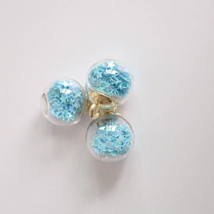 Macro detail of three 16mm glass ball charms with sky blue star sequins and gold hooks
