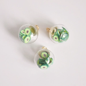 Macro view of 16mm glass globe pendants with miniature avocado slices for DIY jewelry