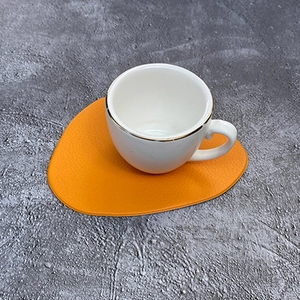 Nordischer orangefarbener PU-Leder-Untersetzer in Kieselform auf grauem Untergrund