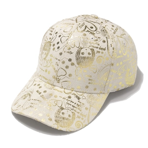 Close-up of beige baseball cap with gold glitter girl portraits and floral print
