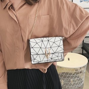White geometric patchwork crossbody chain bag with gold lock shown on model outfit