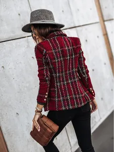 Detail of red tweed blazer sleeve with gold buttons and intricate plaid pattern
