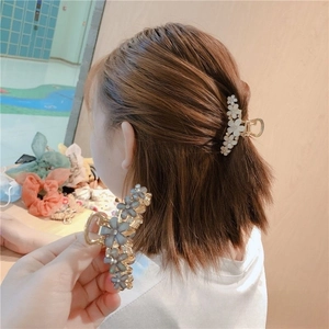Detailed view of elegant floral hair claws with pearl luster petals on golden alloy base