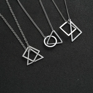 Detail of four silver geometric pendant necklaces with triangles and squares on textured background