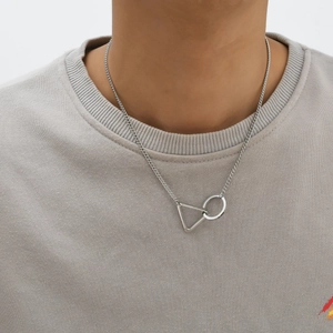 Close-up of a silver geometric triangle and circle pendant necklace on a grey t-shirt