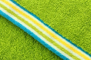 Close-up of green cotton towel with soft terry texture and colorful striped edge detail