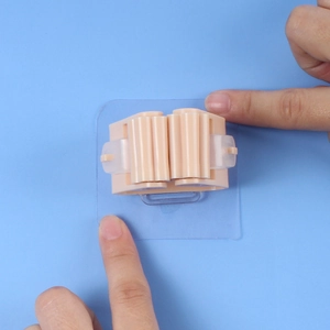 Beige wall-mounted mop holder with strong adhesive being applied to a blue wall