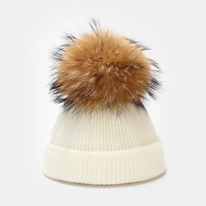 Detail of white ribbed knit baby beanie featuring a large fluffy faux fur pom-pom