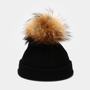 Close-up of the ribbed knit texture and fluffy faux fur pompom on this black winter hat