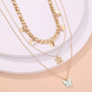 Detailed macro view of triple layered gold butterfly and LOVE pendant necklace set