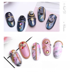 Detail of nail art chains with golden metal, pearls, rhinestones and marble patterns
