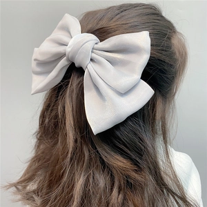 Detail showing high-shine silver organza bow hair clip worn by model for elegant styling