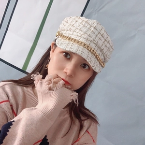 Detailed close-up of tweed newsboy cap featuring elegant gold metal chain and plaid pattern