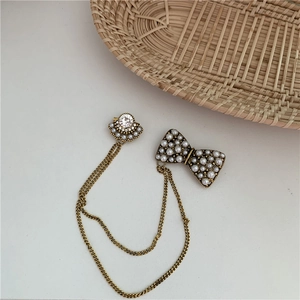 Detailed view of Baroque bow brooch with pearls and rhinestones on gold double chains