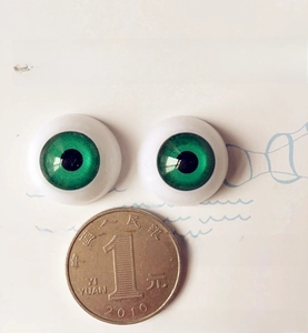Close-up of 20mm green doll eyes with a 1-yuan coin for scale comparison