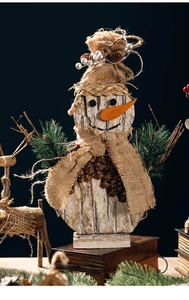 Detail of handmade wooden snowman with pine cones and burlap scarf on vintage book base