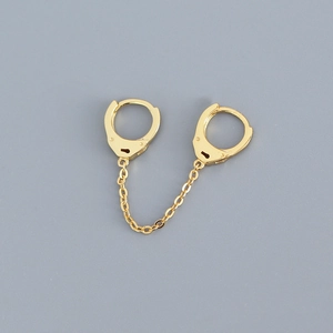 Detailed view of gold handcuff link earrings with chain on a professional grey background