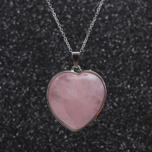 Polished stainless steel chain necklace with pink crystal heart pendant on black background