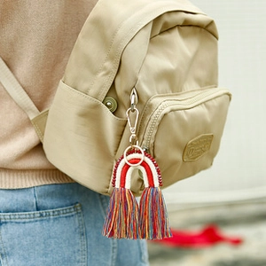 Gros plan d'un charme arc-en-ciel tissé avec cordes en coton colorées sur un sac à dos