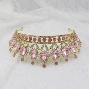 Macro detail of gold crown with pink teardrop rhinestones on white lace fabric
