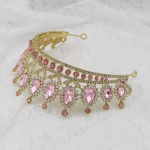 Detail of golden Baroque crown featuring pink teardrop gems and sparkling rhinestones