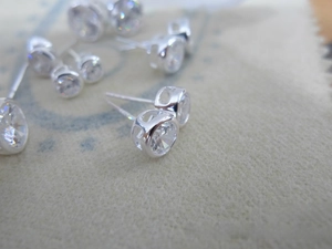 Close-up of 925 sterling silver stud earrings featuring round bezel-set cubic zirconia