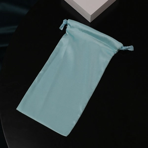 Light blue silk drawstring bag for jewelry and small gift packaging on a black background