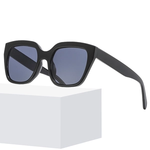 Chic black oversized square sunglasses with dark grey lenses on white geometric pedestal